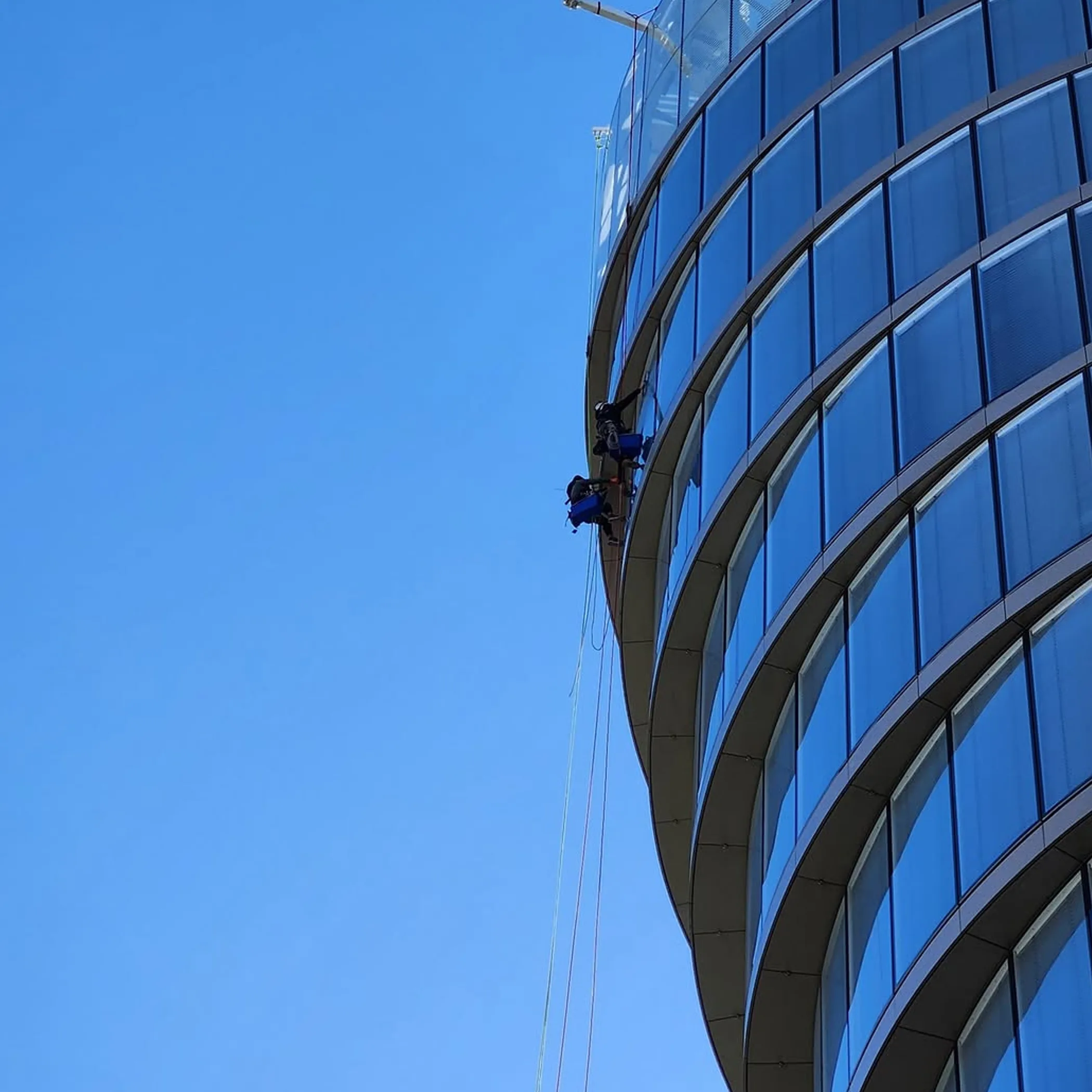 rope-access cleaners on curved building overhang